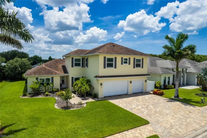 View of front of house with a front lawn, stucco siding, decorative driveway, and a garage