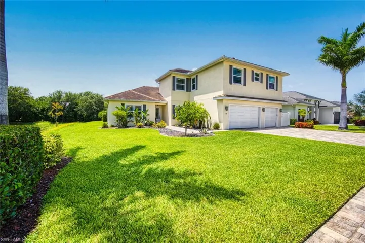 View of front of home featuring stucco siding, a garage, a front yard, and decorative driveway