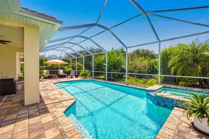 View of pool with a patio area, a pool with connected hot tub, ceiling fan, and glass enclosure