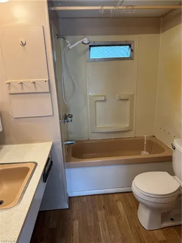 Full bathroom with shower / washtub combination, wood-type flooring, vanity, and toilet