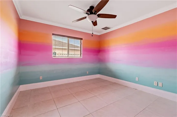 Spare room featuring ornamental molding, light tile patterned floors, and ceiling fan