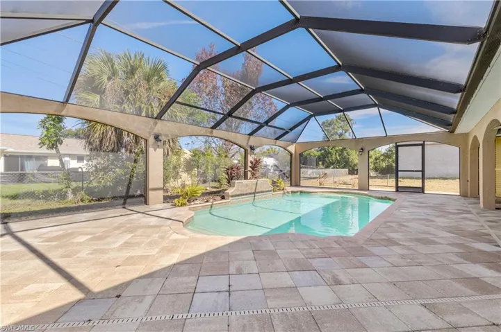 Outdoor pool with a sunroom, glass enclosure, and a patio