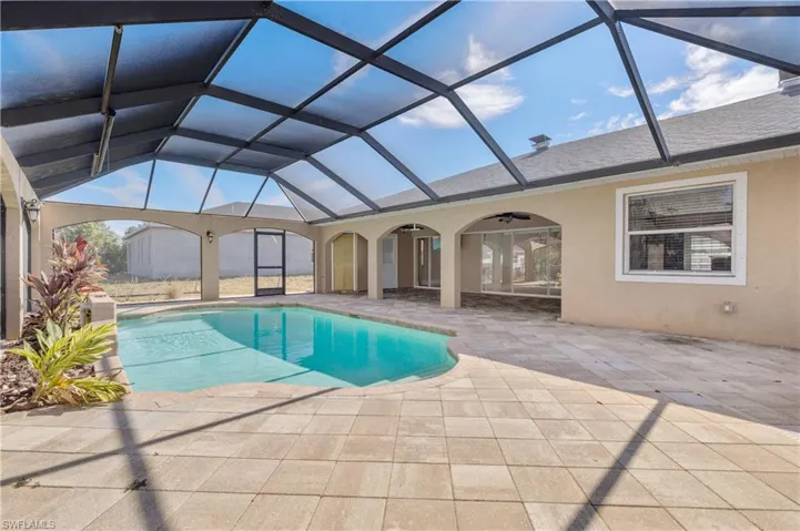 Outdoor pool with a sunroom, a patio, and glass enclosure