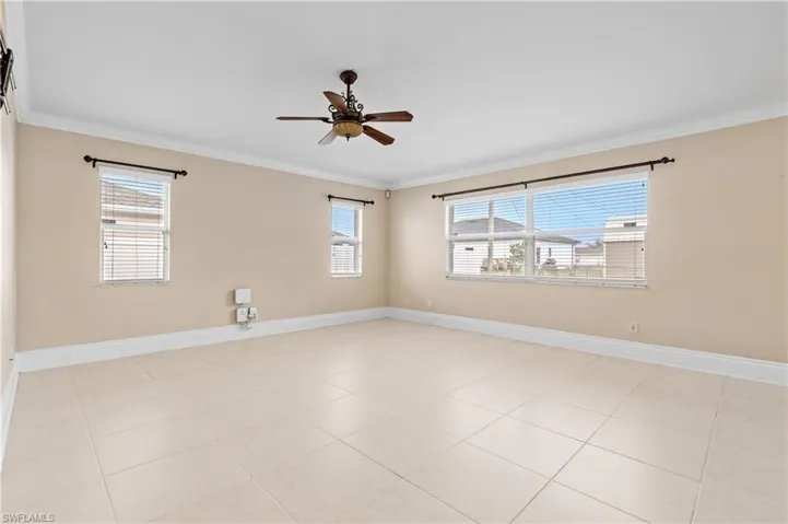 Unfurnished room with a ceiling fan, plenty of natural light, crown molding, and light tile patterned floors