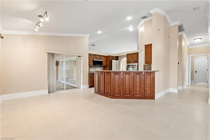 Kitchen with crown molding, brown cabinets, a peninsula, tasteful backsplash, and appliances with stainless steel finishes