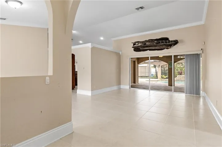 Spare room with arched walkways, ornamental molding, light tile patterned floors, and recessed lighting