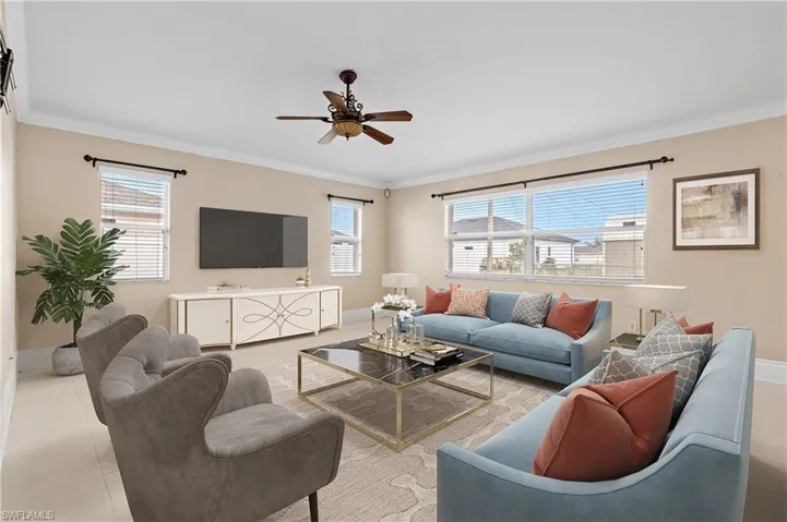 Tiled living area featuring a ceiling fan and ornamental molding