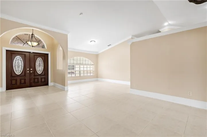 Entryway featuring ornamental molding, light tile patterned flooring, and vaulted ceiling