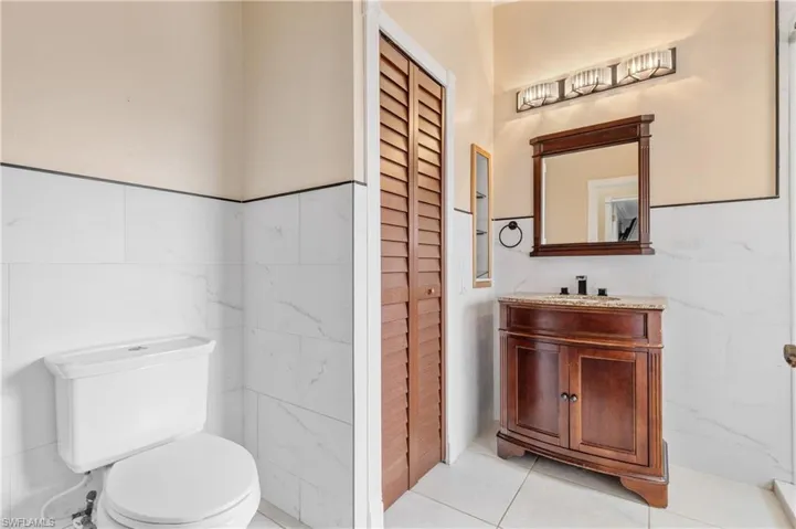 Guest bathroom featuring vanity, tile walls, light tile patterned flooring, and a closet