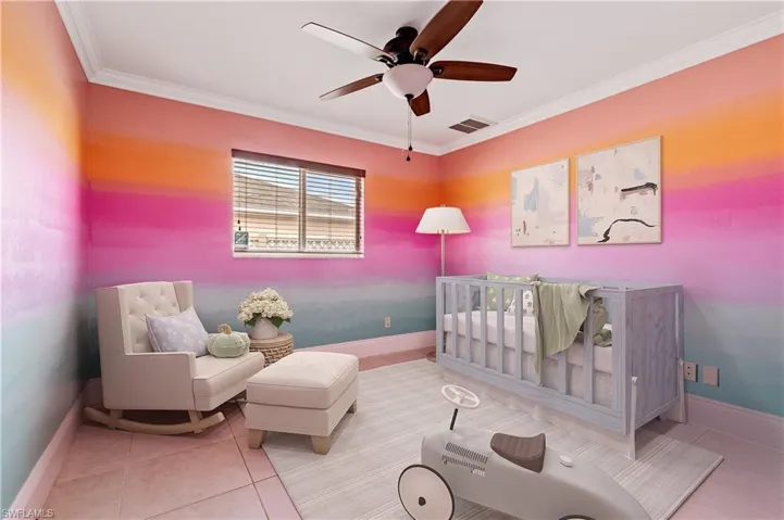 Bedroom 2 featuring a nursery area, ornamental molding, ceiling fan, and tile patterned floors
