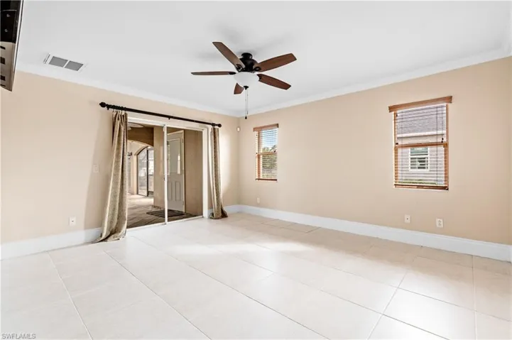 Primary bedroom with access to exterior, ornamental molding, multiple windows, a ceiling fan, and light tile patterned flooring