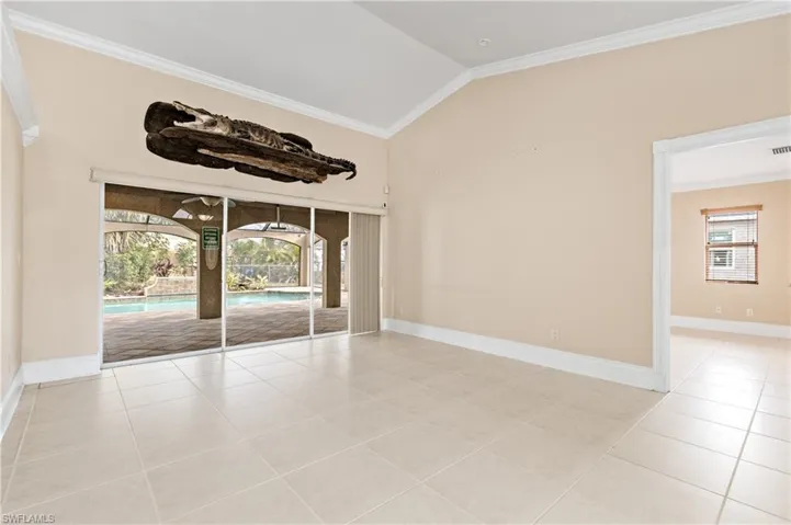 Spare room featuring crown molding, a sunroom, lofted ceiling, and light tile patterned floors