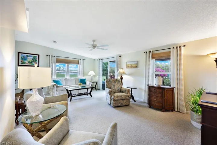 Carpeted living room with ceiling fan and vaulted ceiling