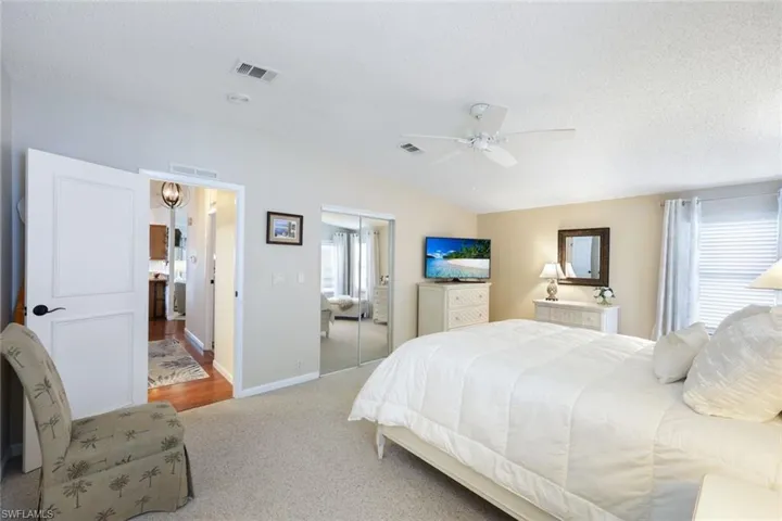 Carpeted bedroom with a textured ceiling, ceiling fan, a closet, and vaulted ceiling