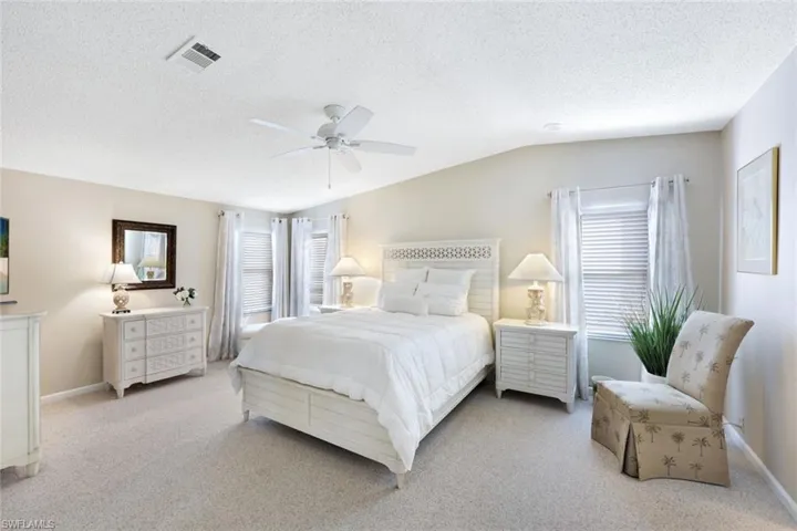 Bedroom with ceiling fan, lofted ceiling, a textured ceiling, and multiple windows