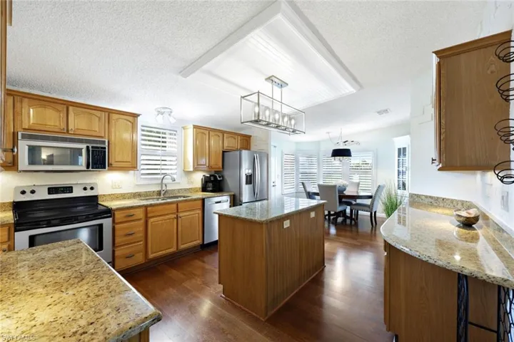 Kitchen featuring a center island, sink, hanging light fixtures, appliances with stainless steel finishes, and dark hardwood / wood-style flooring