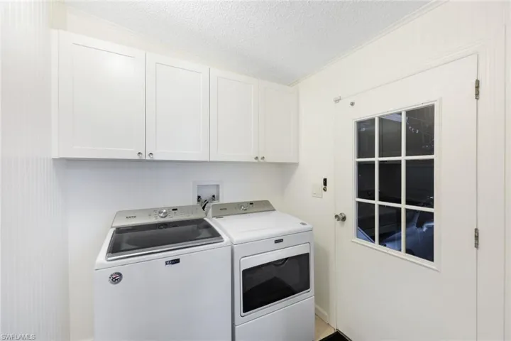 Laundry area featuring cabinets, a textured ceiling, separate washer and dryer, and ornamental molding