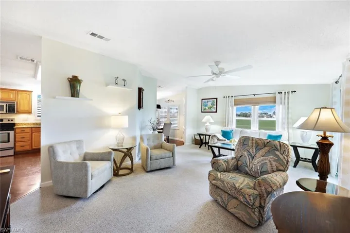 Carpeted living room with ceiling fan and a textured ceiling