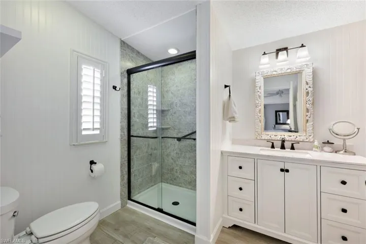 Bathroom featuring wood-type flooring, vanity, toilet, and an enclosed shower