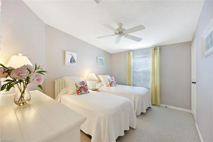 Carpeted bedroom with a textured ceiling, ceiling fan, and lofted ceiling