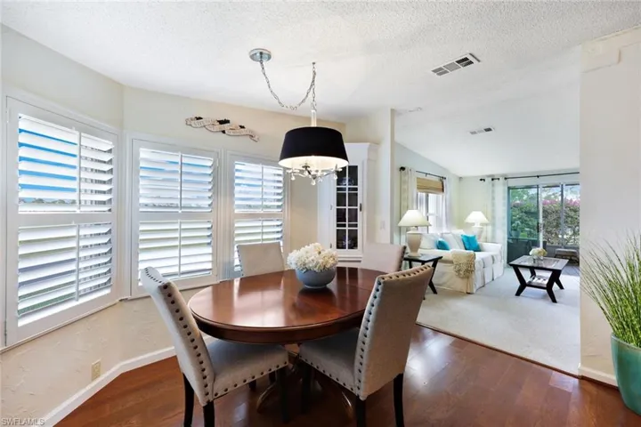 Dining area featuring a textured ceiling, dark hardwood / wood-style flooring, an inviting chandelier, and vaulted ceiling