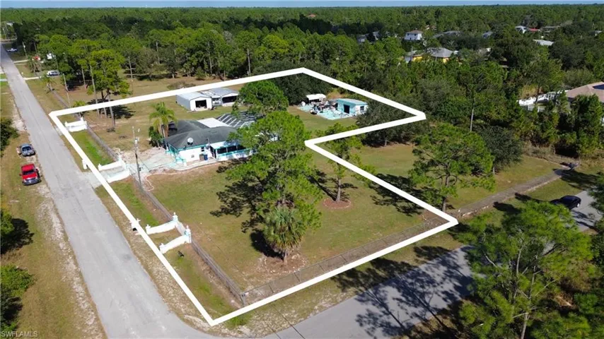 Aerial view of property and surrounding area featuring property boundaries highlighted and a heavily wooded area