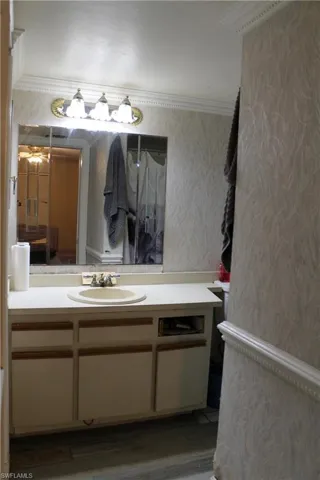 Bathroom with vanity, wallpapered walls, and ornamental molding