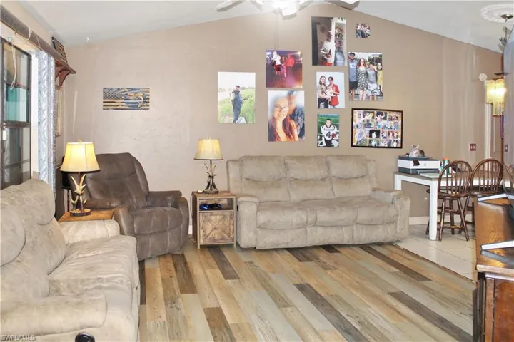 Living area with vaulted ceiling, light wood finished floors, and a ceiling fan