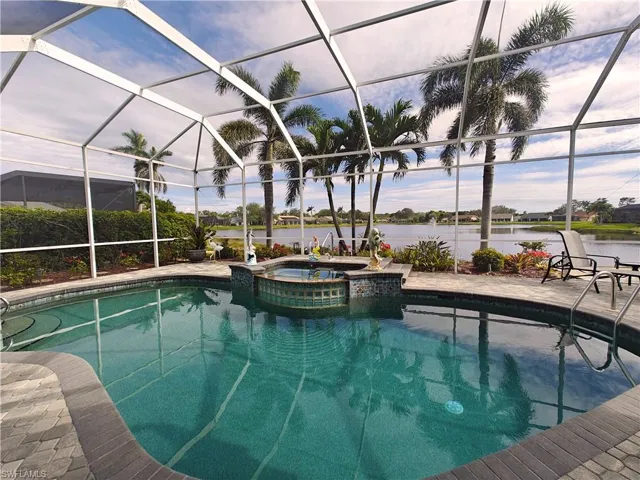 View of swimming pool with a patio, a water view, a pool with connected hot tub, and a lanai