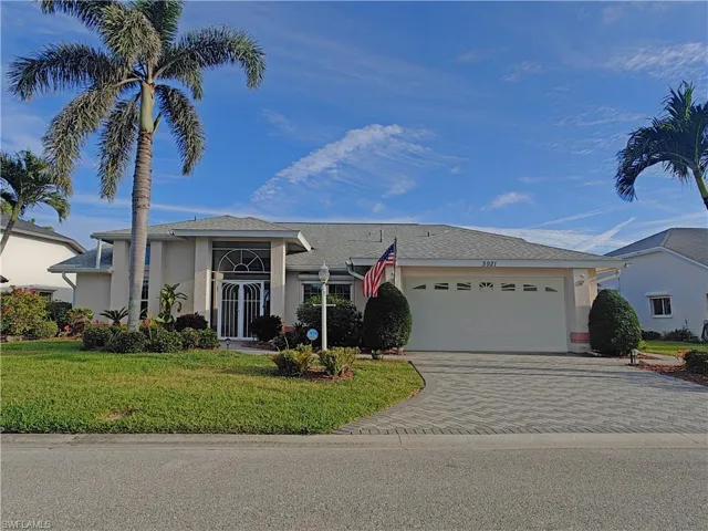 View of front of home with a front yard, decorative driveway, an attached garage, and stucco siding