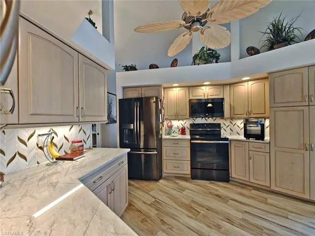 Kitchen with light wood finished floors, backsplash, black appliances, and ceiling fan