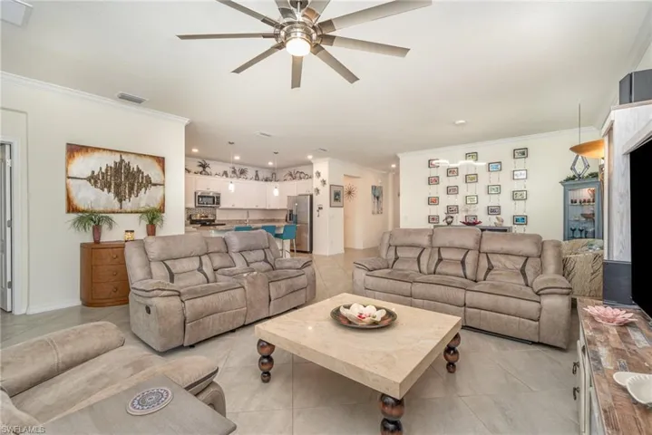 Tiled living room featuring ornamental molding and ceiling fan