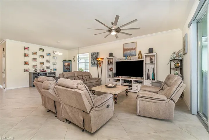 Tiled living room featuring ornamental molding and ceiling fan