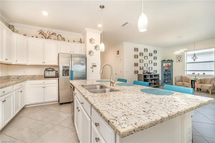 Kitchen featuring light tile patterned floors, a kitchen island with sink, and sink