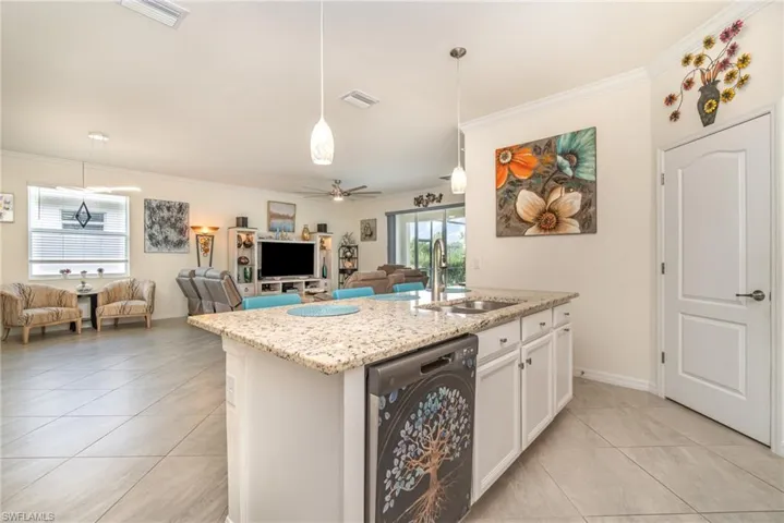 Kitchen with sink, dishwashing machine, light tile patterned floors, white cabinetry, and ceiling fan
