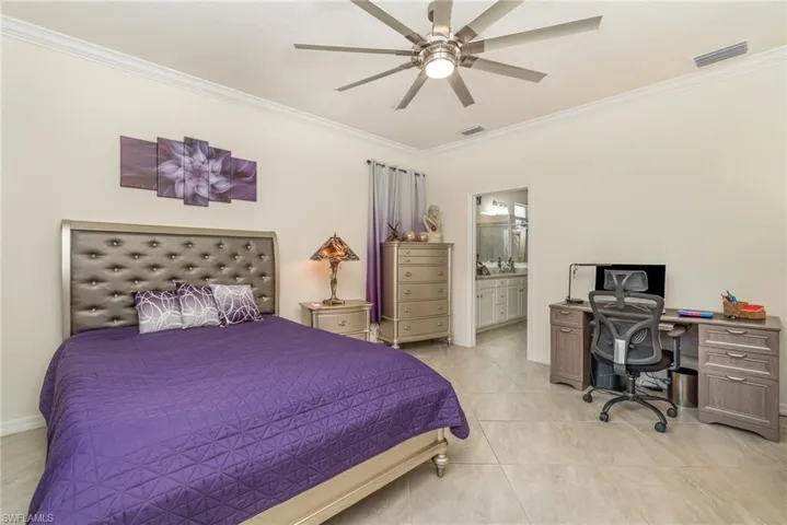 Bedroom with ensuite bathroom, ornamental molding, light tile patterned floors, and ceiling fan