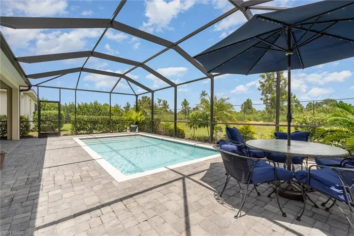 View of pool featuring glass enclosure and a patio area