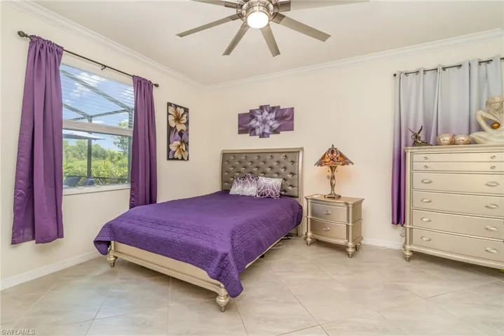 Bedroom with light tile patterned flooring, ornamental molding, and ceiling fan