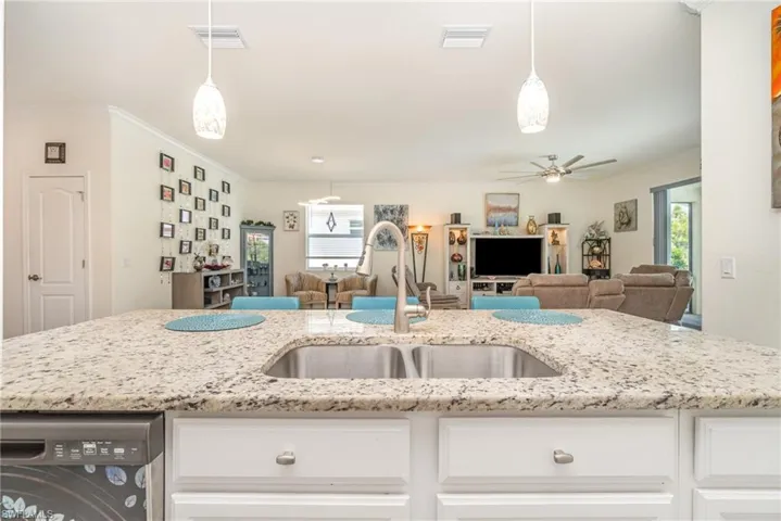 Kitchen featuring hanging light fixtures, light stone countertops, crown molding, and ceiling fan
