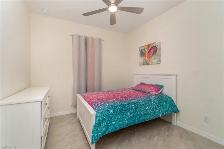 Tiled bedroom featuring ceiling fan