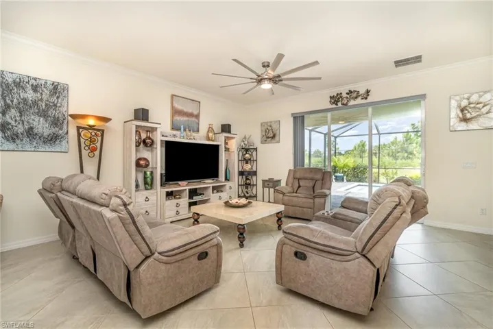 Living room featuring light tile patterned flooring, crown molding, and ceiling fan