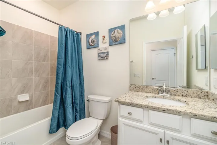 Full bathroom with vanity, shower / bath combo, and toilet