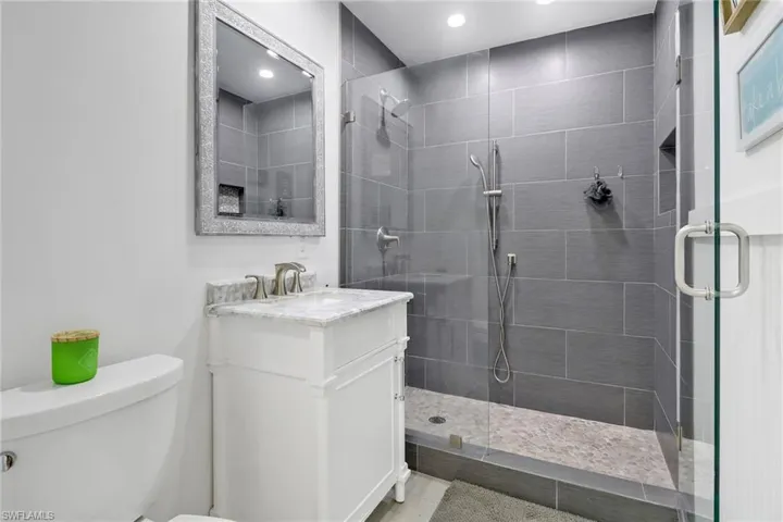 Bathroom featuring a shower with door, vanity, and toilet