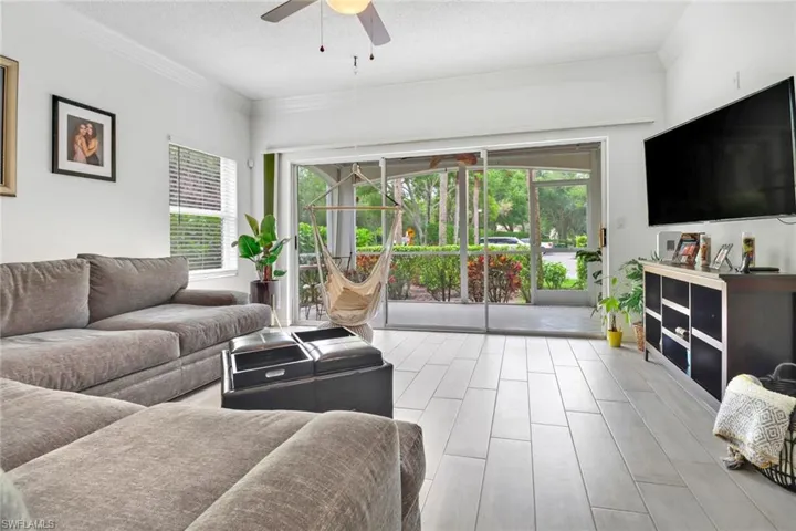 Living room with crown molding, light hardwood / wood-style flooring, ceiling fan, and a textured ceiling