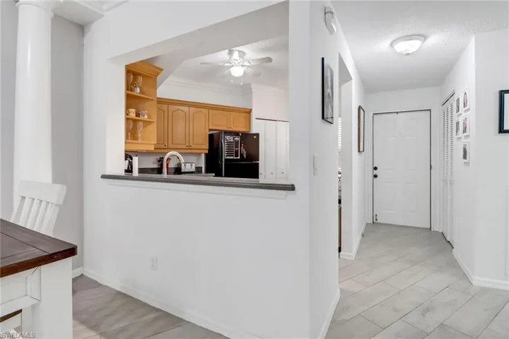 Kitchen featuring ceiling fan, black refrigerator, light brown cabinets, ornamental molding, and light hardwood / wood-style floors