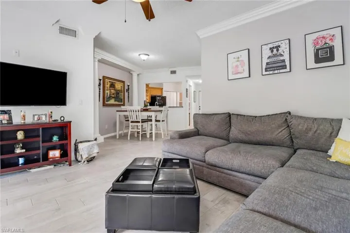 Living room featuring light wood-type flooring, ceiling fan, and ornamental molding