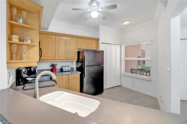 Kitchen with range, light hardwood / wood-style flooring, sink, black refrigerator, and ceiling fan