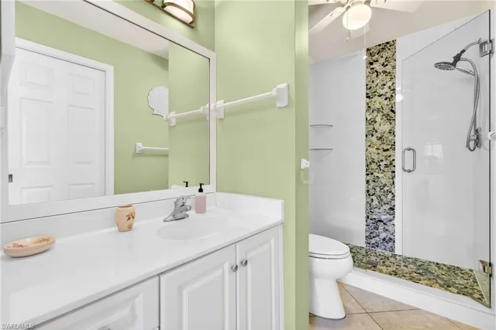 Bathroom with a stall shower, vanity, light tile patterned floors, and a ceiling fan