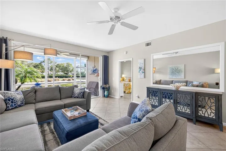 Tiled living room featuring a ceiling fan and baseboards