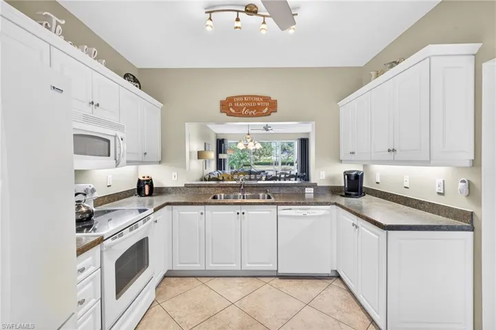 Kitchen with white appliances, white cabinets, and light tile patterned flooring